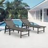 Two grey lounge chairs are placed on a patio next to a swimming pool with palm trees in the background. Produktbild-Vorschau