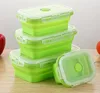 A stack of green collapsible silicone food storage containers with white lids on a wooden surface. Náhled obrázku produktu
