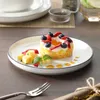 A dessert is presented on a white plate with a black rim, garnished with berries and mint, on a wooden table. Náhled obrázku produktu
