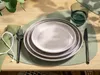 A table setting with plates, cutlery, a napkin, and a glass on a placemat. Produktbild-Vorschau