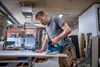 A man is using a jigsaw in a workshop. Anteprima dell’immagine prodotto