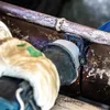 A close-up view of a reciprocating saw blade cutting a metal pipe. Voir les images du produit