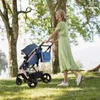 A woman pushing a stroller in a park. Produktbild-Vorschau