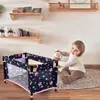 A young child is playing with a stuffed animal next to a doll's travel crib. Produktbild-Vorschau