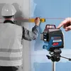 A construction worker is using a Bosch laser level to mark a line on a wall. Another person's hand is shown adjusting the laser. Anteprima dell’immagine prodotto