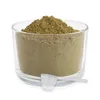 A clear, well-lit studio shot of a glass container filled with brown powder, with a small white scoop resting in front of it. Produktbild-Vorschau