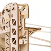 A close-up view of a wooden marble run construction kit, showing a metal ball on a track. Voir les images du produit