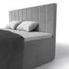 A close-up view of a gray upholstered box spring bed with white pillows and a dark gray blanket. Produktbild-Vorschau