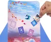 A hand is placing a small square image onto a larger card with illustrations and numbered squares. Náhľad obrázku produktu