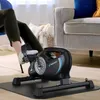 A person is using a mini exercise bike in a living room setting. Náhľad obrázku produktu