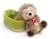 A sleeping plush hedgehog toy holding a small mushroom, next to a green basket. Produktbild-Vorschau