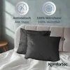 Two black pillowcases are laid out on a white bed with a gray tufted headboard in the background. There are informational icons and text above the pillows. Produktbild-Vorschau
