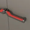 A close-up view of two gray and black handles with red accents on a gray surface, likely a cabinet or door. Voir les images du produit