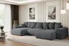 A large, dark gray sectional sofa is positioned in a modern living room setting with artwork on the wall and a coffee table nearby. Produktbild-Vorschau