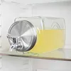 A glass beverage dispenser filled with yellow liquid, placed on a shelf inside a refrigerator. Produktbild-Vorschau