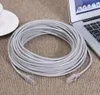 A coiled gray Ethernet cable is placed on a textured brown surface, next to a laptop and a white cup and saucer. Produktbild-Vorschau