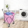 A pink shopping trolley filled with clothes in a laundry room next to a washing machine. Voir les images du produit
