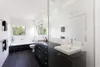 A modern bathroom with a bathtub, toilet, and vanity with a large mirror. Produktbild-Vorschau
