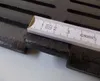 A close-up of a cast iron grate with a ruler measuring a section of it. Voir les images du produit