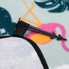 A close-up of a picnic blanket with a flamingo pattern and a stake attached. Náhled obrázku produktu