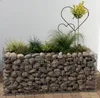 A raised garden bed filled with plants and decorative stones. Náhled obrázku produktu
