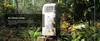 A portable air conditioner placed on a stump in a forest setting. Produktbild-Vorschau