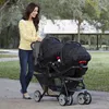 A woman pushing a double stroller in a park. Voir les images du produit