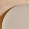 A close-up view of a round, beige table surface against a textured, beige wall. Produktbild-Vorschau