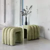 Two green upholstered ottomans are placed in a modern interior with concrete walls and a large window. Produktbild-Vorschau