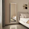 A bedroom scene with a tall, illuminated LED mirror on the wall next to a bed. Anteprima dell’immagine prodotto