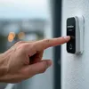 A hand is pressing a doorbell button on a wall. Náhľad obrázku produktu