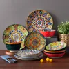 A collection of colorful, patterned ceramic plates and bowls arranged on a wooden surface. Náhled obrázku produktu