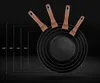A set of frying pans of different sizes, with handles pointing upwards, against a dark background. Dotted lines and measurements indicate the sizes of the pans. Voir les images du produit