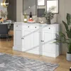 A white sideboard with drawers and doors is placed in a dining or living room setting, with artwork on the wall and a plant nearby. Produktbild-Vorschau