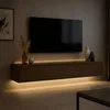 A modern living room with a wall-mounted TV and entertainment unit, illuminated by LED strip lighting. Produktbild-Vorschau