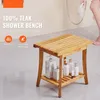 A teak shower bench with bottles of toiletries on the lower shelf, in a bathroom setting with a person showering in the background. Podgląd zdjęcia produktu
