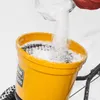Filling a yellow spreader with white granular material, likely salt or fertilizer, in a snowy environment. Produktbild-Vorschau