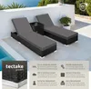 Two black rattan sun loungers with gray cushions are placed on a patio next to a swimming pool, with a small black side table between them. The scene is set outdoors with a white wall and some greenery in the background. Náhled obrázku produktu
