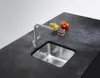 A stainless steel kitchen sink and faucet on a dark countertop, with a small bowl of fruit and nuts nearby. Podgląd zdjęcia produktu