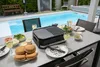 Ein Terrassentisch am Pool ist mit Burgern, Gemüse, Salaten, Weingläsern, Tellern und dem Elektrogri Anteprima dell’immagine prodotto