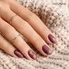 A close-up shot of a woman's hands with burgundy matte nails, adorned with gold leaf designs and rings, resting on a textured cream-colored fabric. Voir les images du produit