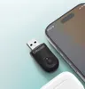A black Ottocast USB adapter is placed next to a smartphone on a light blue surface. Produktbild-Vorschau
