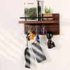A wooden key holder mounted on a white wall, displaying keys, sunglasses, and a small plant. Produktbild-Vorschau