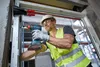 A construction worker installs a window frame using a cordless drill. Náhľad obrázku produktu