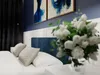 A bedroom scene with a bed, pillows, and artwork on the wall. Produktbild-Vorschau