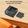 The back of a black electronic lock is shown with the battery compartment open, revealing four AAA battery slots. The battery cover is placed next to the lock on a wooden surface. Náhled obrázku produktu