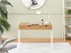A desk with a lamp and a book in a room with a plant and a painting. Voir les images du produit