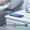 A smartphone is charging on a nightstand next to a sleeping person and an alarm clock. A diagram illustrates the charging process. Produktbild-Vorschau