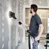 A man is sanding a wall with a long-handled sander. Náhled obrázku produktu