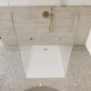 A modern bathroom shower area with a white shower tray and gold fixtures. Anteprima dell’immagine prodotto